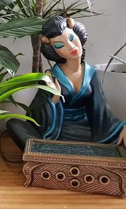 Oriental chalkware figurine in blue kimono sat in front of short table