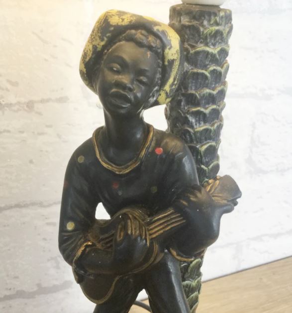 A close up of a chalkware lamp with a musician playing a guitar