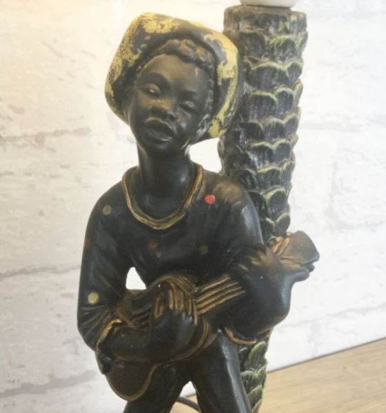 A close up of a chalkware lamp with a musician playing a guitar