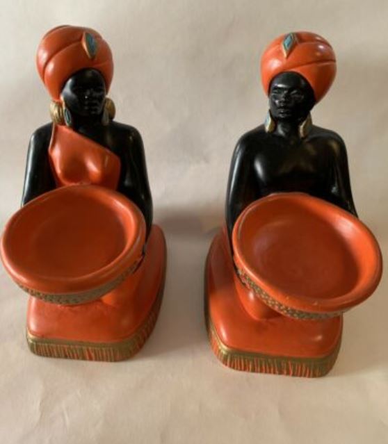 Two black chalkware statutes holding orange bowls