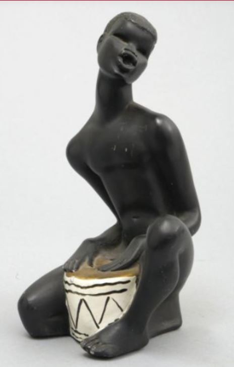 Kneeling drummer in black chalkware with white drum between legs