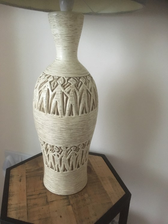 Tall standard lamp showing outlined stick figures in two circles round the cylindrical object